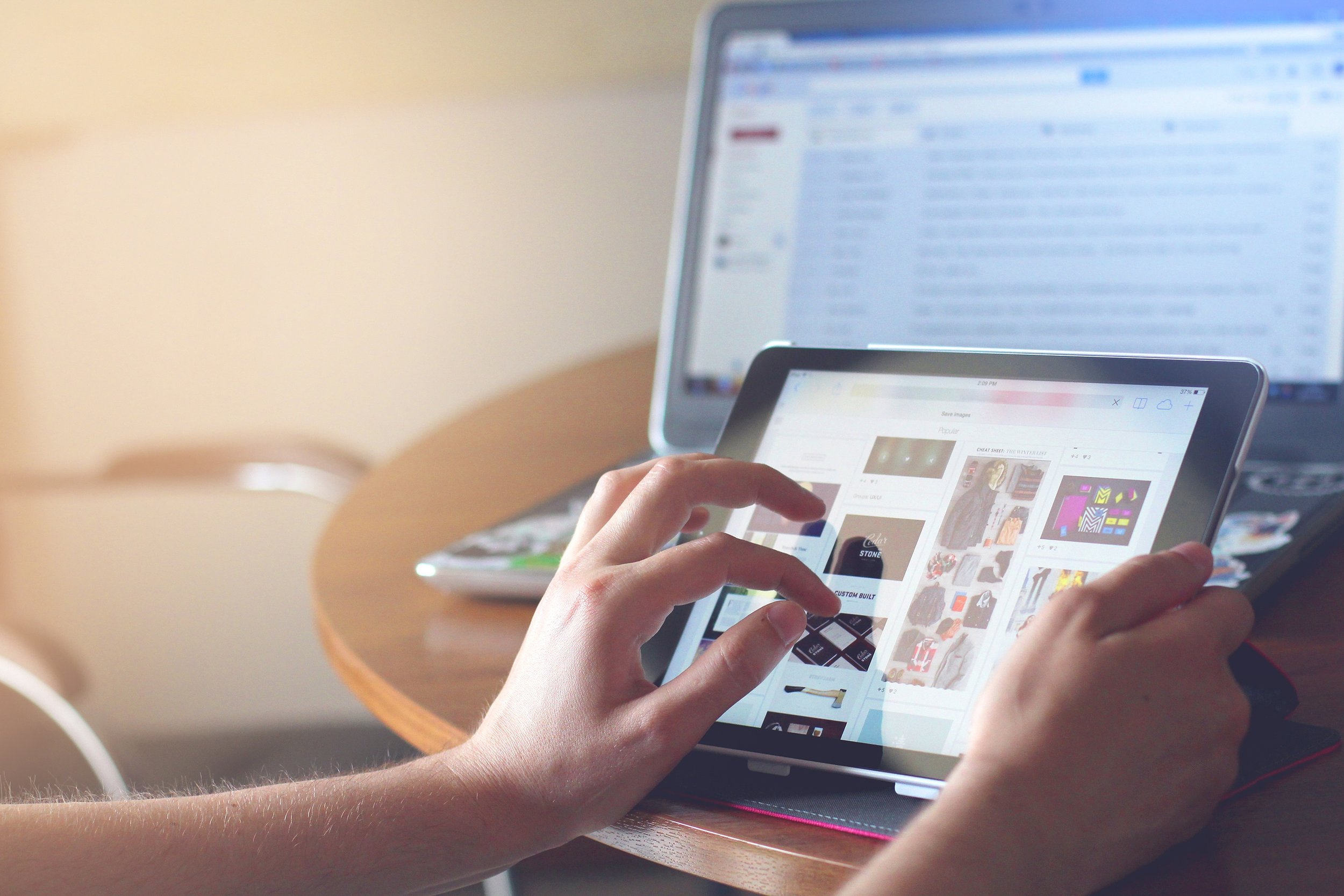 hands playing on a tablet with laptop in background