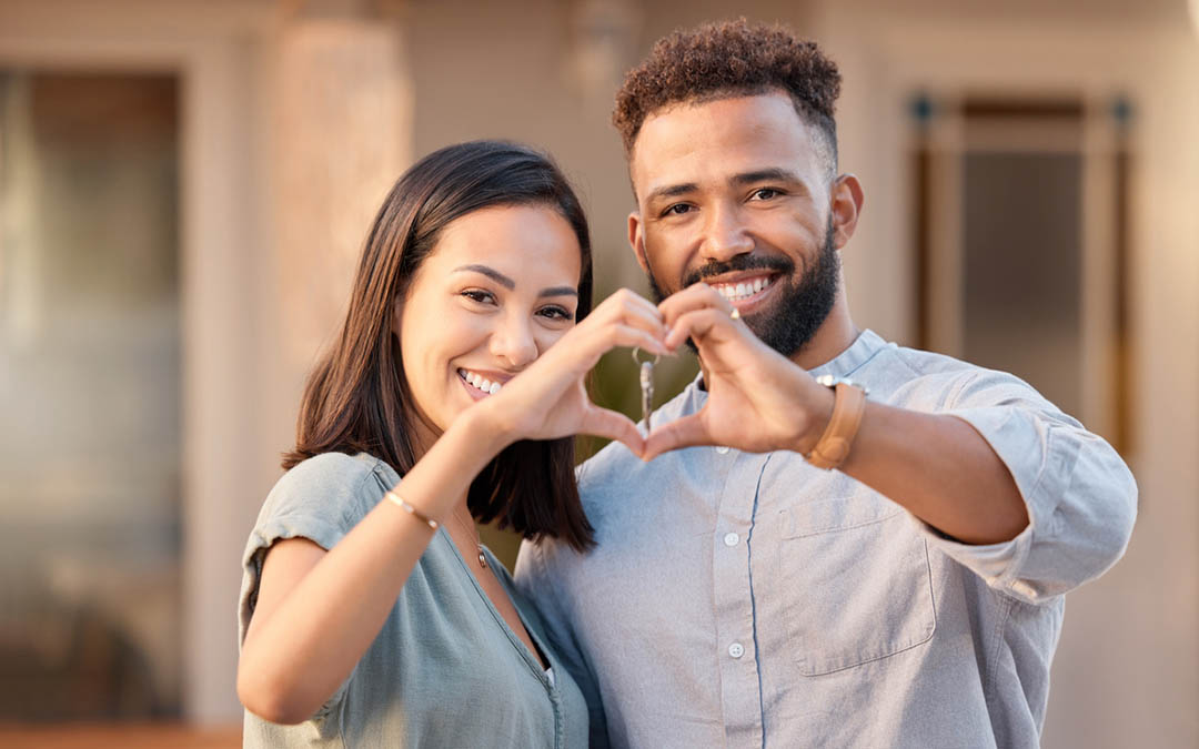 A couple using their hands to make a heart symbol